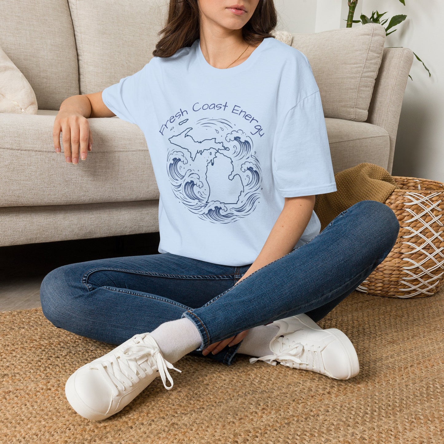 Person sitting on the floor wearing a light blue t-shirt with State of Michigan design, surrounded by waves