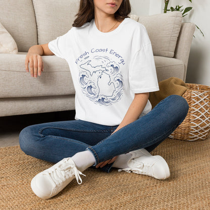 Person sitting on the floor wearing a white t-shirt with a design, blue jeans, and white sneakers in a living room.