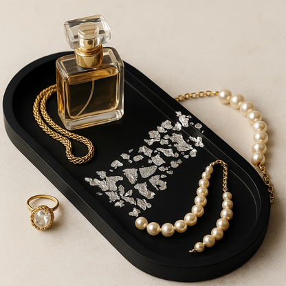 Perfume bottle, necklace, ring, and earrings on a black tray with a beige background