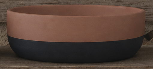 A two-tone ceramic bowl with a matte terracotta upper half and a dark charcoal black lower half, shown on a rustic wooden surface.