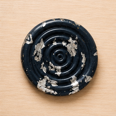 Black ceramic object with decorative patterns on a wooden surface