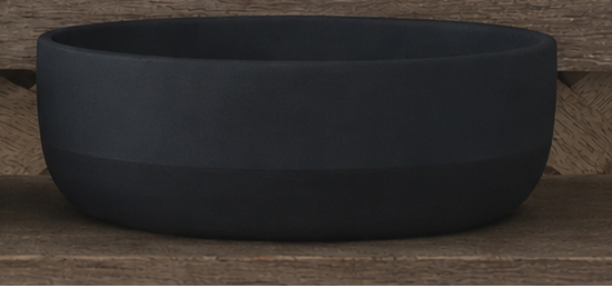 A matte black cement bowl with a wide rim, displayed on a rustic wooden surface.