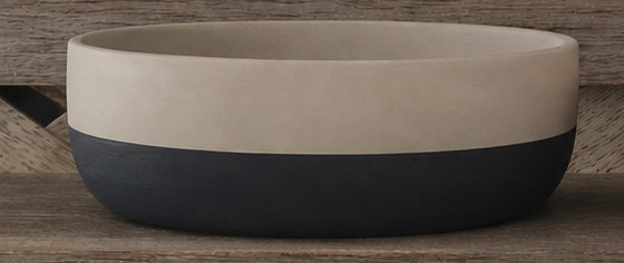 A two-tone cement bowl with a matte cream-colored upper half and a dark charcoal gray lower half, shown on a rustic wooden surface.