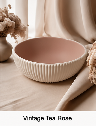 A cement bowl with a ribbed fluted exterior and a matte dusty rose pink interior, styled on a beige fabric surface with dried flowers and draped curtains in the background. The text 'Vintage Tea Rose' is displayed at the bottom.
