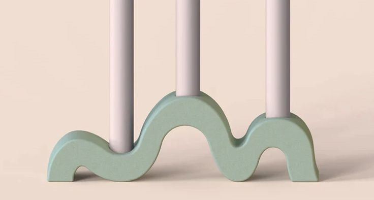 Wavy green candle holder with white candles on a beige background
