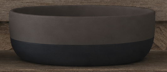 A wide, shallow round bowl with a two-tone design, featuring a matte taupe-brown top half and a dark charcoal-black bottom half, set against a rustic wooden background.