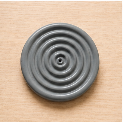 Gray circular object with concentric ridges on a beige surface