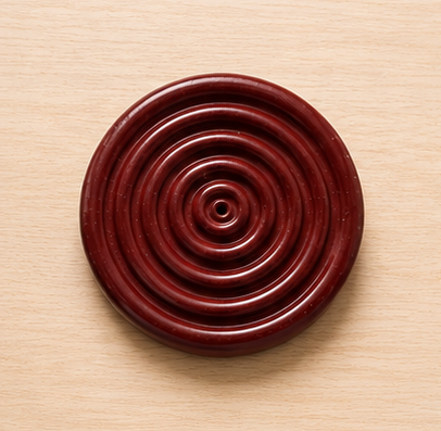 Round wooden object with concentric circles on a beige background