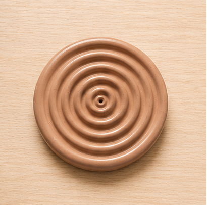 Ceramic incense holder with concentric circles on a wooden surface
